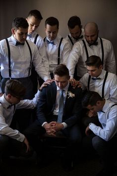 a group of men in suits and ties standing around each other with their hands together