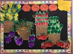 a bulletin board with vegetables and fruits on it, in front of a black background