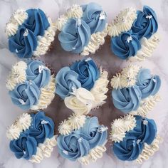 cupcakes decorated with blue and white icing on a marble table top, arranged in the shape of a flower