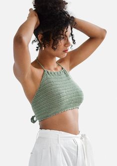 a woman in white shorts and a green crop top with her hands on her head