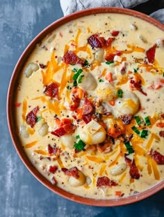 a bowl filled with soup and cheese on top of a blue table next to a napkin