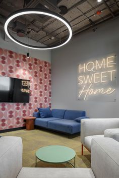 a room with couches, chairs and a television on the wall in front of a neon sign