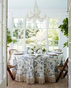 a dining room with a table and chairs in front of a window that has a chandelier hanging from the ceiling