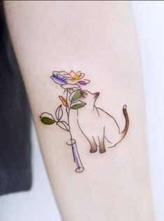 a cat with a flower tattoo on its leg is sitting next to a person's arm