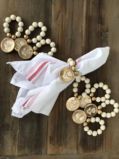 white napkins with red and gold buttons on them sitting on a wooden table next to other items