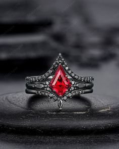 a close up of a ring with a red stone in the center on a black surface