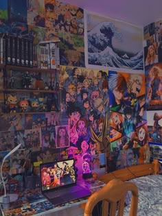 a desk with a laptop computer sitting on top of it next to a wall covered in anime pictures