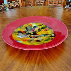 a colorful plate sitting on top of a wooden floor next to a table with chairs