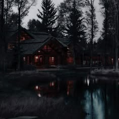 a cabin is lit up at night by the water