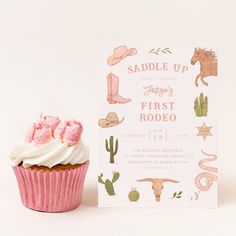 a cupcake with frosting next to a card for a cowboy themed baby shower