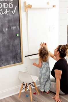 a woman and child are playing with a chalkboard