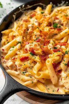 a skillet filled with macaroni and cheese on top of a wooden cutting board