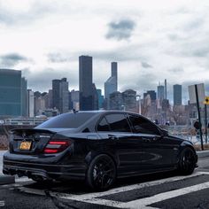 a black car parked in front of a city skyline