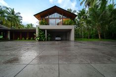 a car is parked in front of a modern house with palm trees and landscaping around it