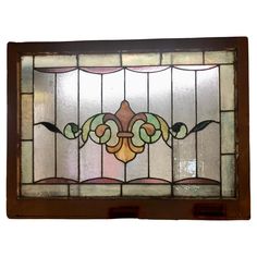 an old stained glass window with decorative designs on the top and bottom panel, hanging from a wooden frame