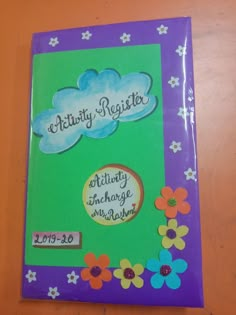 a purple and green activity book with flowers on the cover, sitting on a table