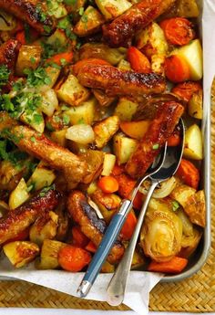 a tray filled with meat and veggies on top of a wooden table next to utensils