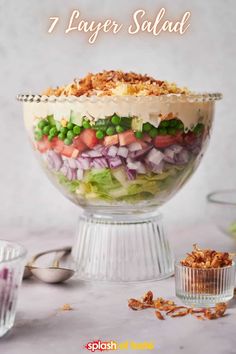 a layered salad in a glass bowl with the words 7 layer salad on top and an image