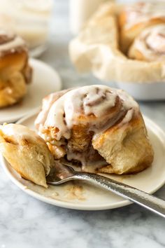 a plate with cinnamon rolls on it and a fork in the foreground, next to other pastries