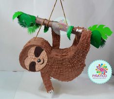 a paper mache sloth hanging from a tree branch