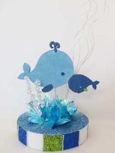 a blue whale cake topper sitting on top of a round box with streamers