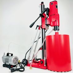 a machine that is sitting on top of a table next to a red bucket and some wires