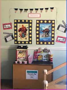 a display in the corner of a room with movie posters on the wall and popcorn