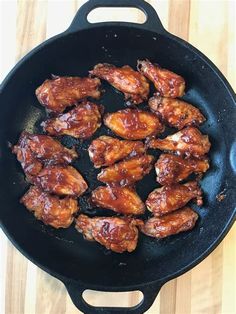 chicken wings cooking in a skillet on a wooden table