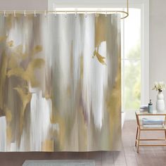 a shower curtain with an abstract painting on it in a white and gold bathroom setting