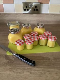 a cutting board topped with jars filled with liquid next to a knife on top of a counter