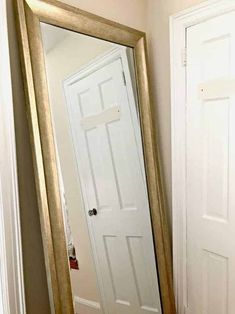 a large mirror sitting on top of a floor next to a white door in a room