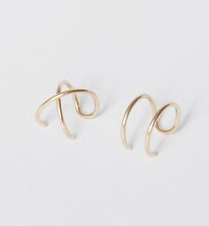 two pairs of gold earrings sitting on top of each other