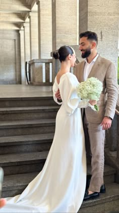 a bride and groom are standing on the stairs