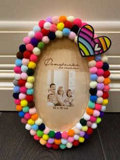 a multicolored photo frame with pom - poms around it