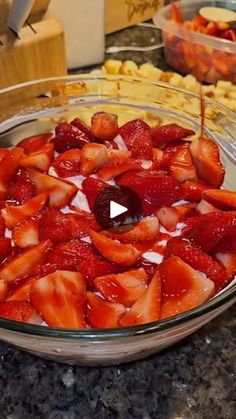 a glass bowl filled with sliced strawberries on top of a counter