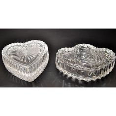 two crystal heart shaped dishes on a black table