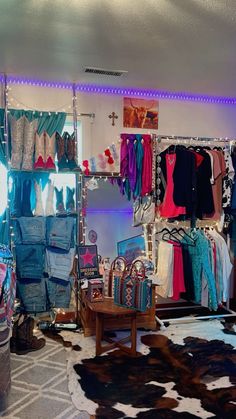 a room filled with lots of clothes and bags next to a cowhide rug on the floor