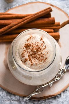 a plate with cinnamon sticks and a drink in it on top of a wooden board