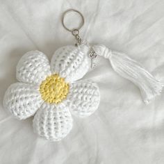 a crocheted flower keychain with a tassel on the end is laying on a white sheet