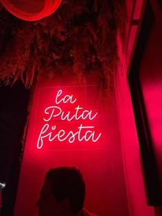 a man sitting in front of a neon sign that says la pitta fiesta