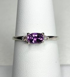 a close up of a ring with a purple stone in it on a white surface