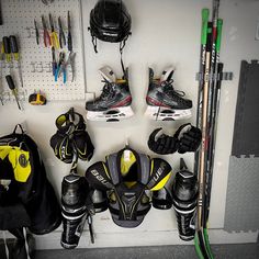 several pairs of hockey equipment are hanging on the wall