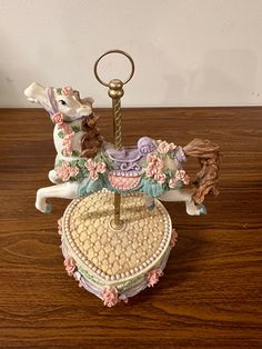 a small carousel horse with flowers on it's back and a key chain hanging from the front