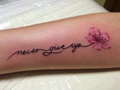 a tattoo with the words never give up and a pink flower on it's arm