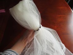 a person wearing a white tulle and beaded bracelet on top of a wooden table