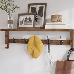 a wooden shelf with two hooks on it and a bag hanging from the wall next to it