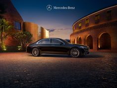 a black car parked in front of a building at night with the words mercedes - benz on it