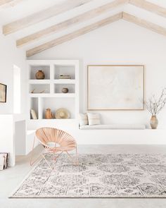 a living room with white walls and wooden beams on the ceiling is filled with bookshelves