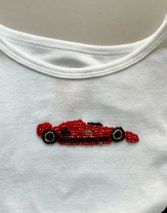 a white shirt with a red car embroidered on it