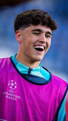 a young man smiling and wearing a purple shirt with the words champion league on it